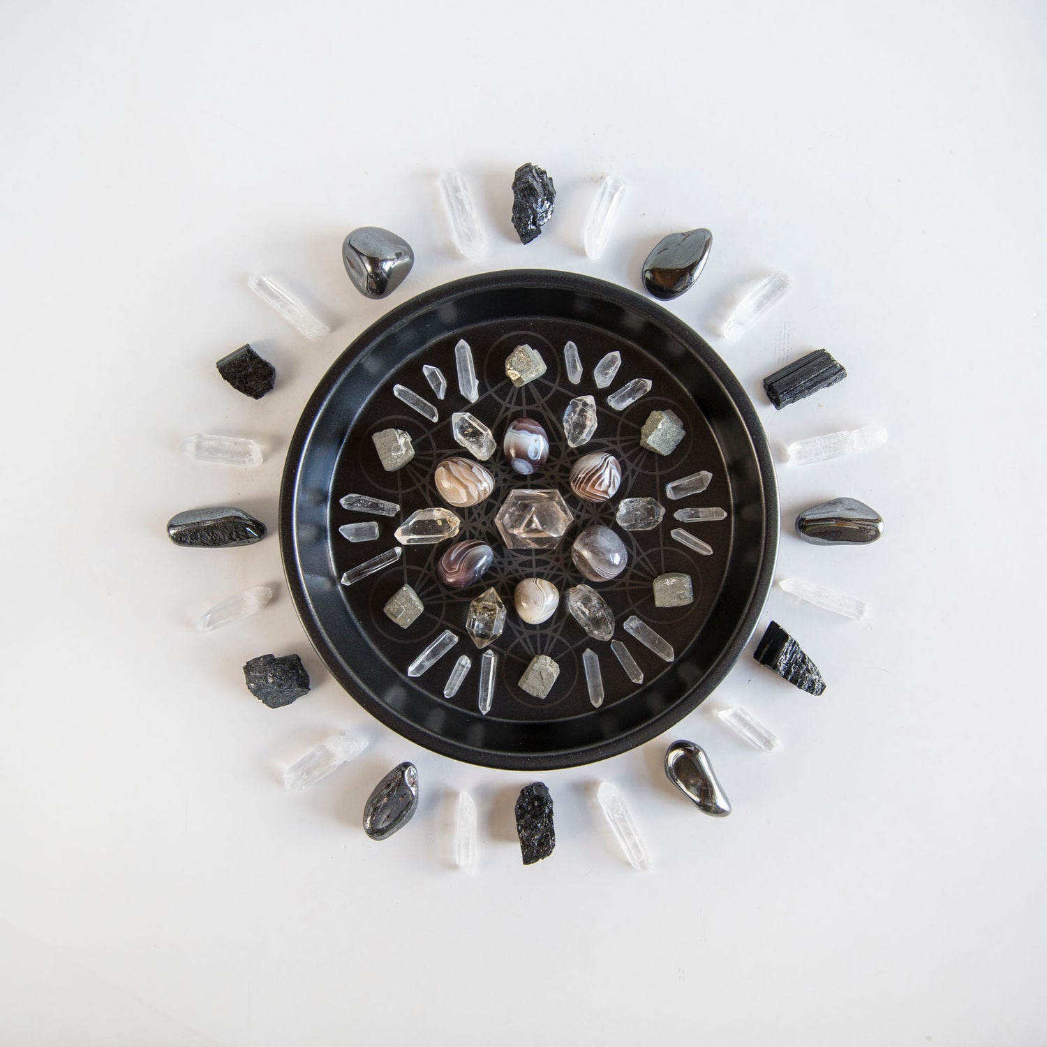 Black dish with a crystal grid on it on a white background
