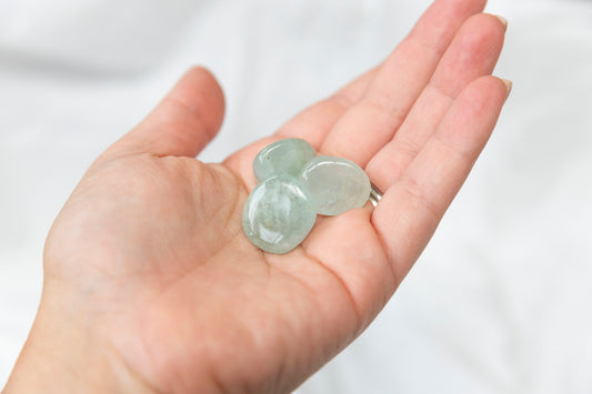 Three aquamarine crystal tumblestones held in a hand against a white background