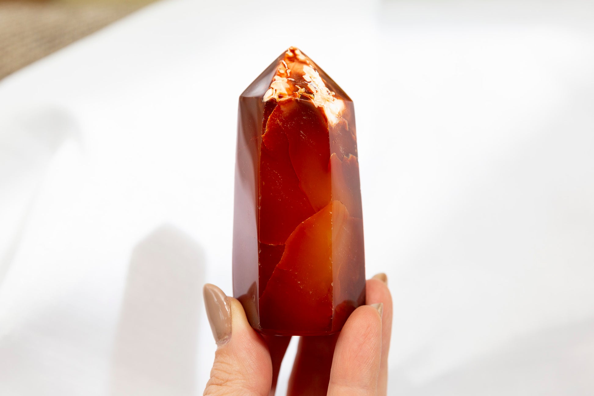 Hand holding a red crystal against a white background