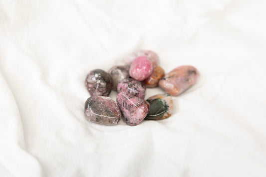 Collection of pink cobaltoan calcite tumblestones on a white background