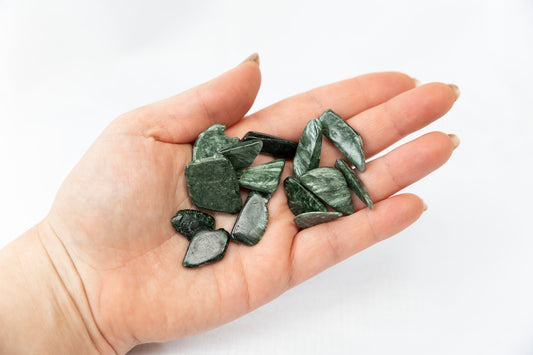 Hand holding green stones against a white background